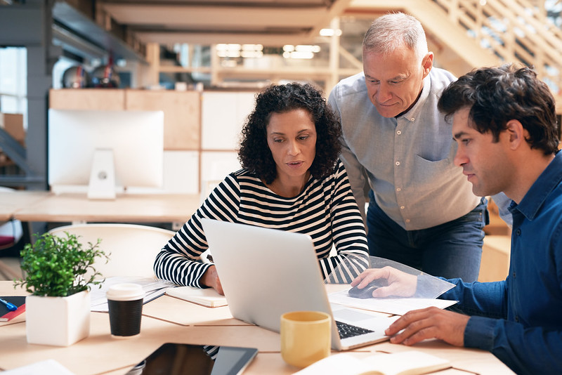 3 adults looking at a laptop