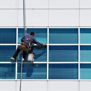 Man cleaning the window on the side of a building