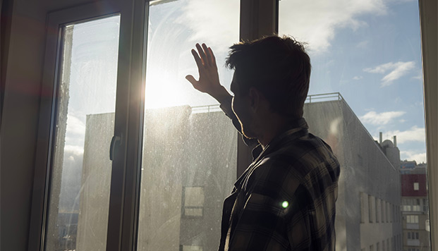 man with raised arm standing by window daylighting