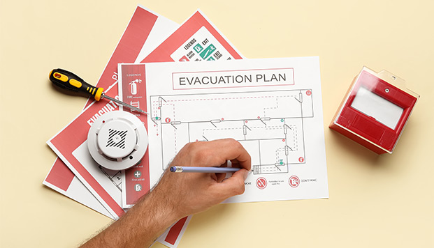 fire prevention week man with smoke detector and fire call point drawing evacuation plan on yellow background